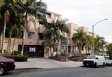 Los Angeles apartment for rent - a building with palm trees and cars parked in front of it