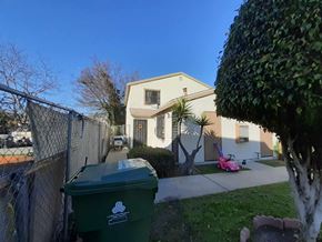 Los Angeles apartment for rent - A green trash bin with a logo on it is in the foreground of a residential street.