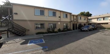 Los Angeles apartment for rent - A parking lot in front of a building with a car parked in the handicap spot.
