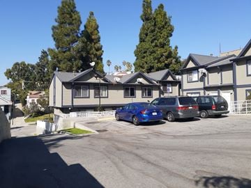 Los Angeles apartment for rent - A blue car is parked in front of a grey building.