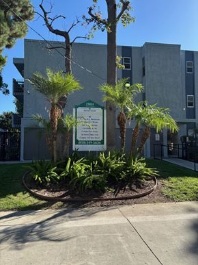 Reseda apartment for rent - A sign in front of a building with trees and plants.