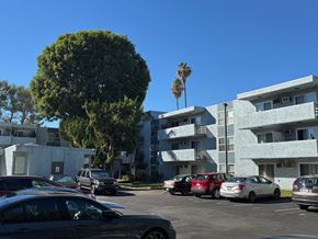 Reseda apartment for rent - A parking lot with cars and apartment buildings in the background.