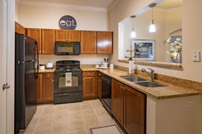 Gainesville apartment for rent - U shaped kitchen with black appliances at The Bartram, Gainesville, Florida 32608