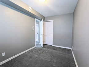 Brandon apartment for rent - a empty living room with gray carpet and a white door