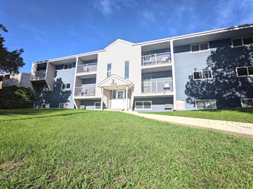 Brandon apartment for rent - an exterior view of an apartment building with a green lawn