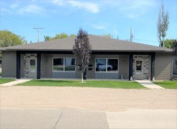 Brandon apartment for rent - the front of a gray building with a lawn and a tree