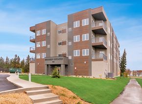 Portage La Prairie apartment for rent - an apartment building with a green lawn and steps in front of it