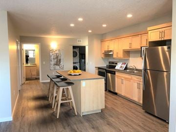 Portage La Prairie apartment for rent - a kitchen with stainless steel appliances and a bar with three stools