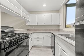 Palm Springs apartment for rent - a kitchen with white cabinets and a black stove top oven
