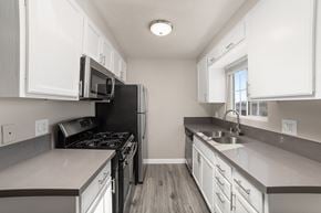 Moreno Valley apartment for rent - A kitchen with white cabinets and a black refrigerator.