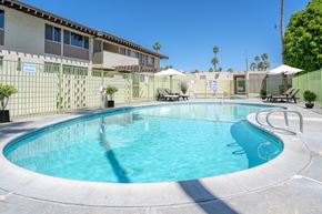 Palm Springs apartment for rent - A swimming pool surrounded by a fence and lounge chairs.