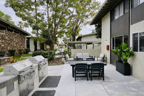 Palm Springs apartment for rent - A patio with a table and chairs is surrounded by a stone wall and trees.