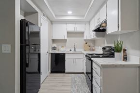 Clovis apartment for rent - A modern kitchen with white cabinets and black appliances.