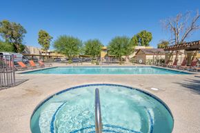 Indio apartment for rent - A swimming pool and a hot tub that is gated and surrounded by lounge chairs.