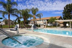 Moreno Valley apartment for rent - a swimming pool with trees and a building in the background