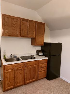Frederick apartment for rent - A kitchen with a black refrigerator and wooden cabinets.