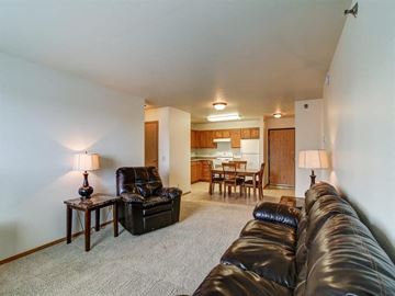 Stanley apartment for rent - A black leather couch sits in a living room with a lamp and a chair.