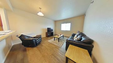 Williston apartment for rent - A living room with a black couch and a wooden table.
