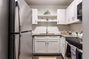 Wheeling apartment for rent - a kitchen with white cabinets and stainless steel appliances and a refrigerator