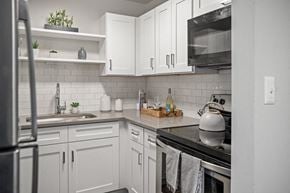 Wheeling apartment for rent - a kitchen with white cabinets and a stove and a sink