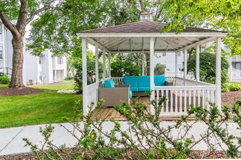 A white gazebo with a blue couch on it
