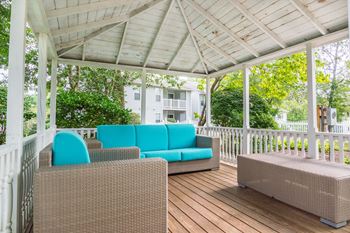 A wraparound porch with wicker furniture and a white pergola