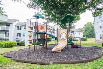 A playground with a slide and climbing equipment in front of an apartment building
