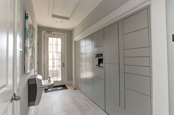 A white hallway with a white door and white tiles on the floor and walls