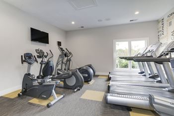A gym with cardio equipment and a flat screen tv