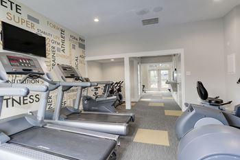 A gym with cardio equipment and a wall of black and white graffiti