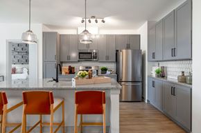 Elkridge apartment for rent - The Forge kitchen with stainless steel appliances and a counter with three orange chairs