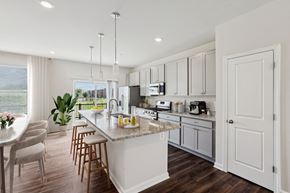Baltimore triplex for rent - an open kitchen and dining room with white cabinets and a marble counter top at Refinery Row, Baltimore, 21224