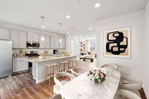Baltimore triplex for rent - an open kitchen and dining room with white cabinets and a marble table at Refinery Row, Baltimore, MD 21224