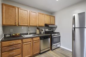 Wheaton apartment for rent - an empty kitchen with wooden cabinets and stainless steel appliances at Earle Manor Apartments, Wheaton, MD