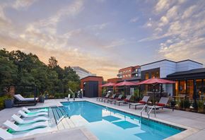 Greenbelt apartment for rent - A swimming pool with red umbrellas and lounge chairs.