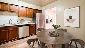 Columbia apartment for rent - A kitchen with a table and chairs in the foreground and a framed picture on the wall at Poplar Glen Apartments, Columbia, MD, 21044.