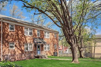 A red brick building with a tree in front.