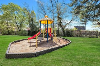 A playground with a yellow and red slide and a yellow tower.