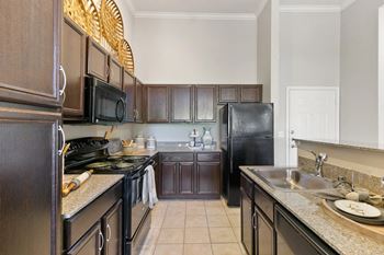A kitchen with black appliances and brown cabinets.