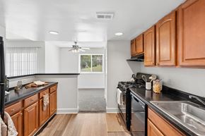 Columbia apartment for rent - Galley kitchen with wood cabinets and black countertops at The Brook At Columbia Apartments, Columbia, Maryland