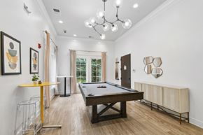 Columbia apartment for rent - A pool table is in the middle of a room with a yellow table and a chandelier  at Poplar Glen Apartments, Columbia, MD, 21044.