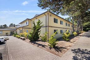 Lincoln City apartment for rent - A yellow building with a parking lot in front.