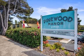 Newport apartment for rent - A sign for Pinewood Manor apartments stands in front of a building.