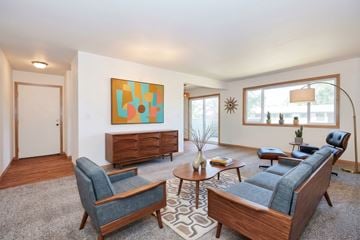 Tigard apartment for rent - A living room with a blue couch, a chair, a coffee table, and a painting on the wall.