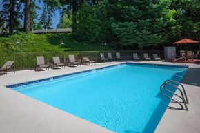 Milwaukie apartment for rent - a swimming pool with deck chairs and trees in the background