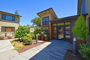 Tigard apartment for rent - A modern building with a glass entrance and a stone pathway leading to it.