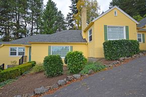 Portland apartment for rent - a yellow house with green shutters and a gravel driveway