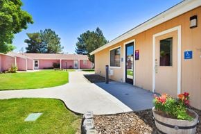 Nyssa apartment for rent - A building with a pink and beige exterior has a walkway leading to the front door.