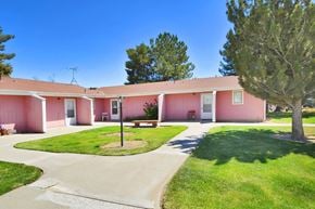Nyssa apartment for rent - A pink building with a green lawn in front.