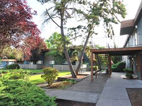Beaverton apartment for rent - a view of the outside of a building with trees and a sidewalk